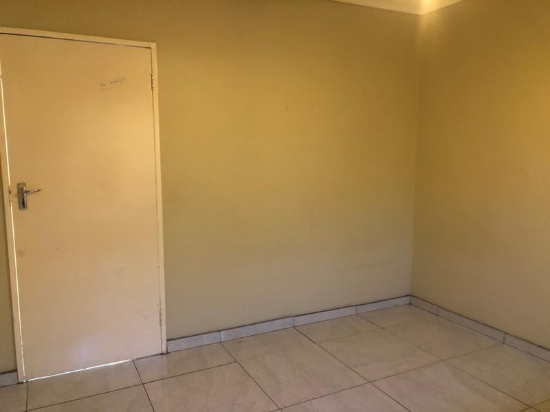 An empty bedroom featuring tiled flooring and neutral wall finishes, providing a blank canvas for potential interior design and staging.