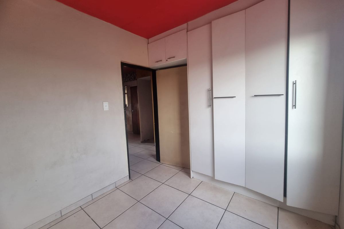 A bedroom featuring built-in cupboards and tiled flooring, offering a functional space ready for personalization.