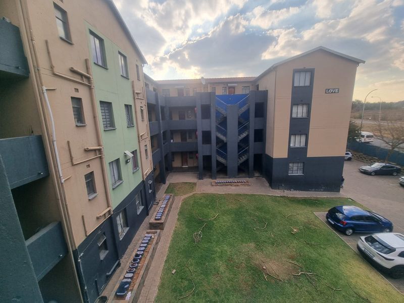 Exterior view of an apartment complex featuring a central courtyard, communal garden, and external stairwell access.