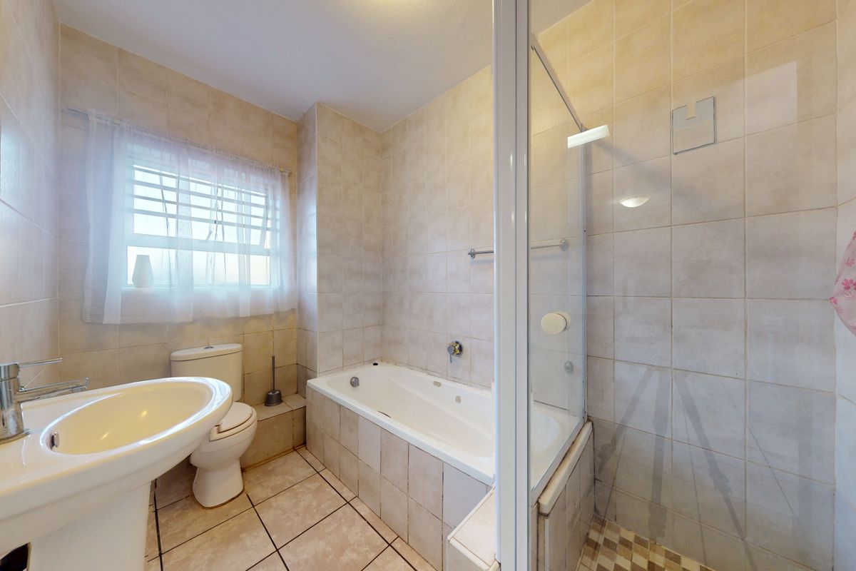 A functional bathroom featuring a pedestal basin, toilet, built-in bathtub, and a separate shower enclosure with tiled finishes throughout.