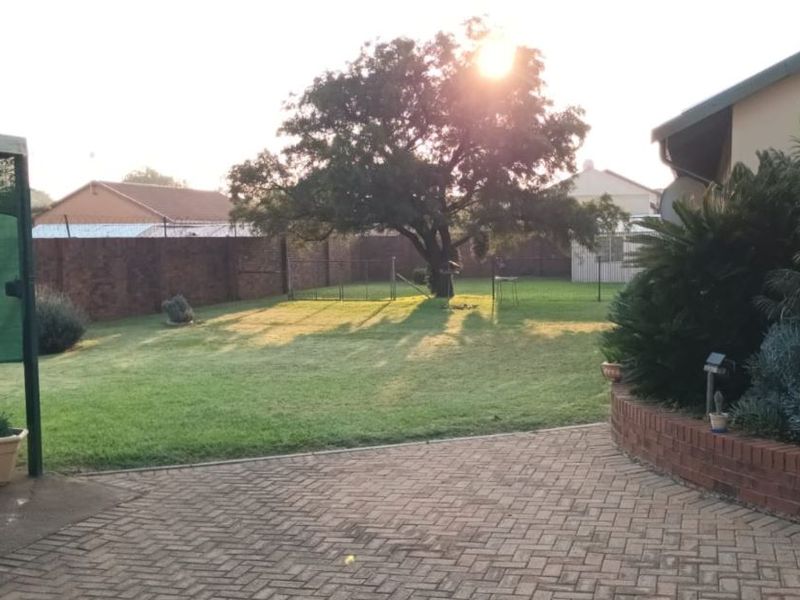 A spacious rear garden featuring a brick-paved patio area, established lawn, and a brick boundary wall, providing a private outdoor space.
