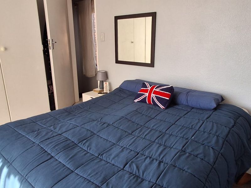 A bedroom featuring built-in cupboards and tiled flooring, providing a functional and neutral space.