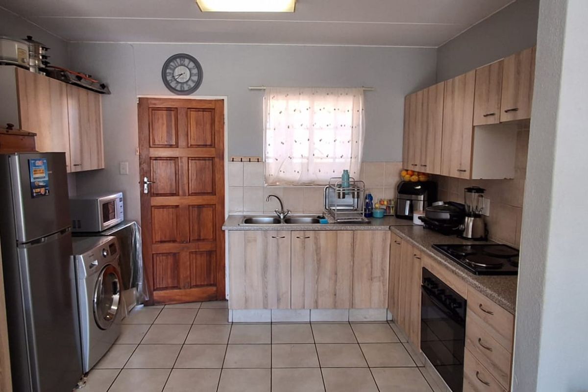 Functional kitchen featuring laminate cabinetry, tiled flooring, built-in oven, electric hob, and a double basin sink with tiled splashback.