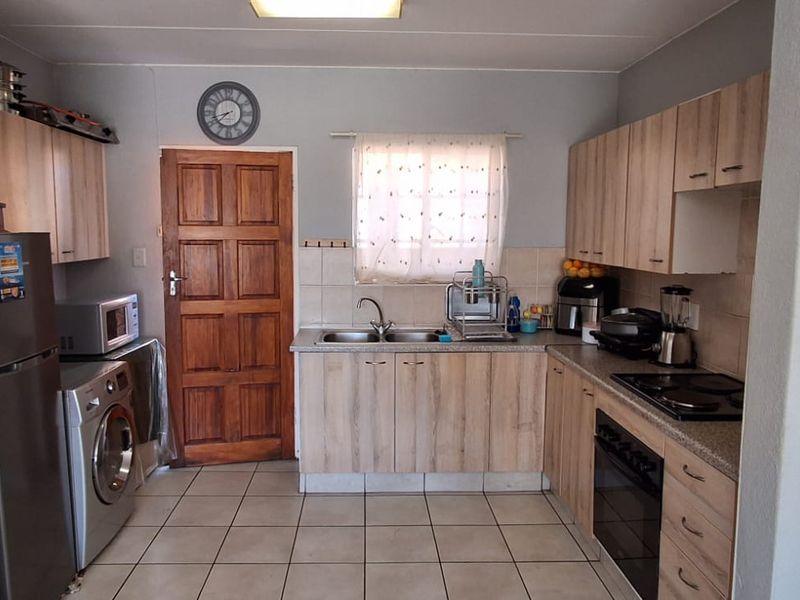 Functional kitchen featuring laminate cabinetry, tiled flooring, built-in oven, electric hob, and a double basin sink with tiled splashback.