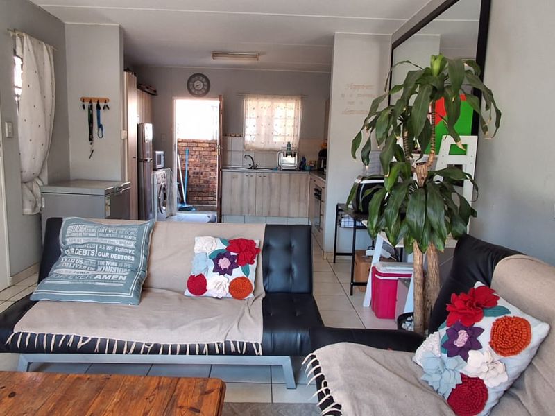 Open-plan living area featuring tiled flooring and a functional kitchen space with built-in cabinetry and sink.