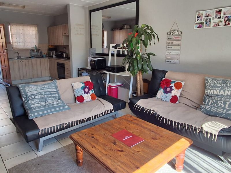 Open plan living area featuring tiled flooring and an adjoining kitchen space with built-in cabinetry and oven.