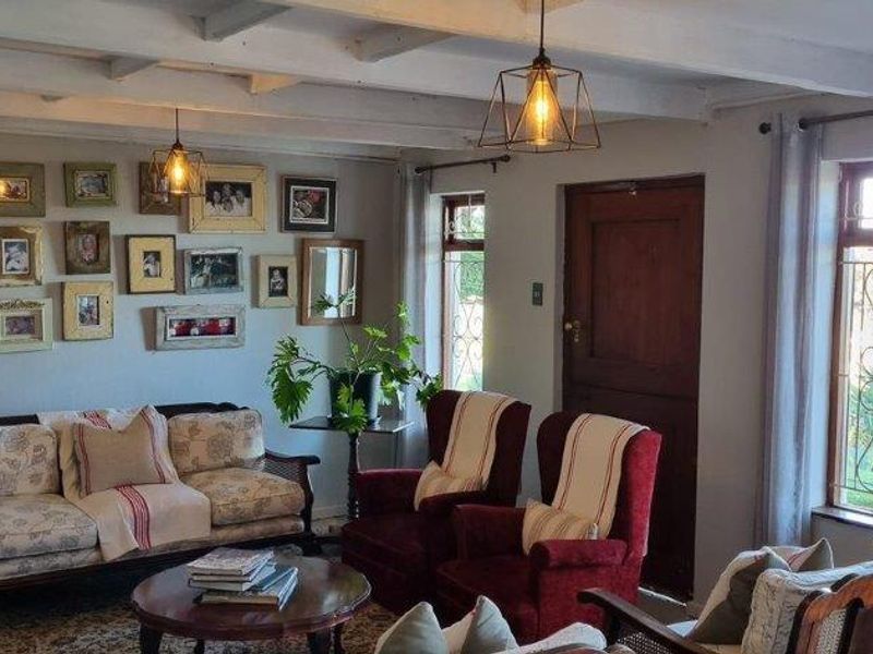 A cozy living room featuring exposed timber ceiling beams, leaded glass windows, and a solid timber door, creating a warm and inviting atmosphere.