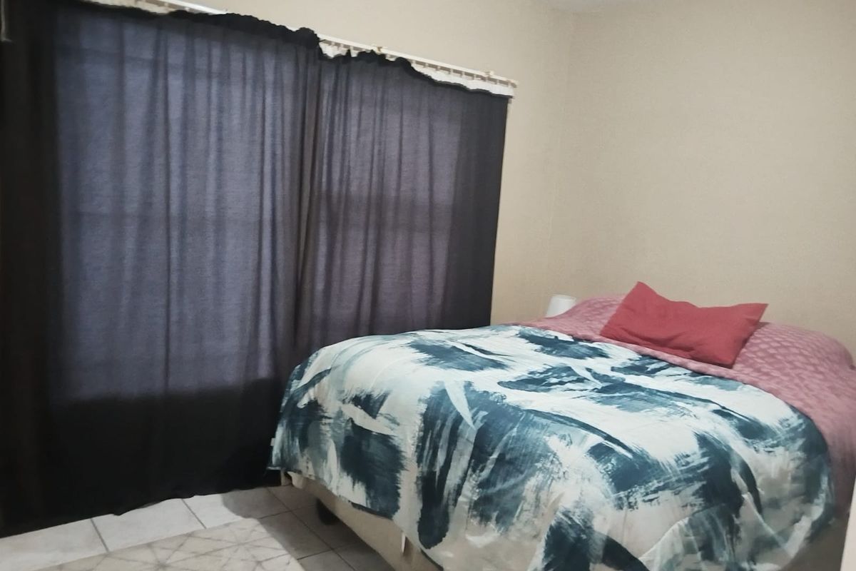 A standard bedroom featuring tiled flooring and neutral wall finishes, providing a functional space for rest.