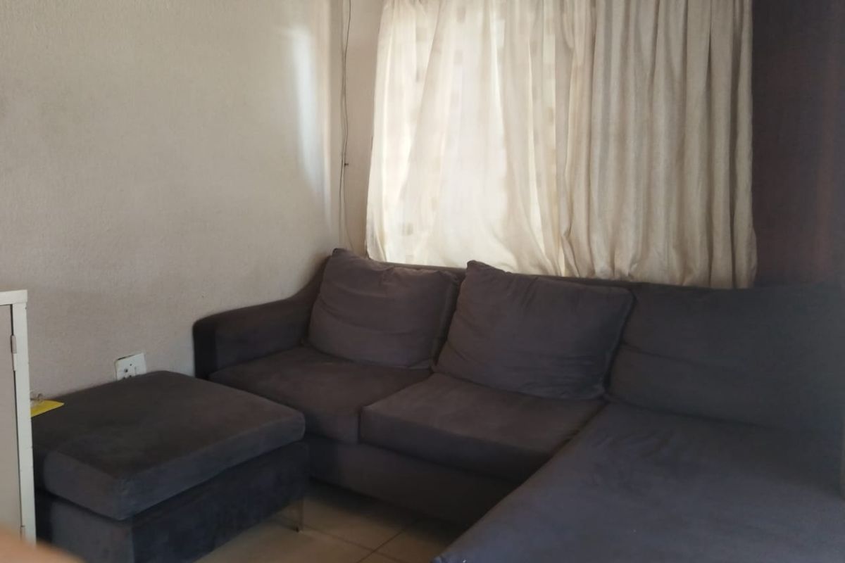 A living room area featuring tiled flooring and window treatments, providing a functional space for relaxation.