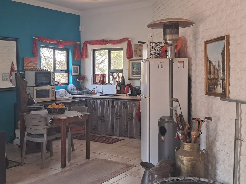 Open plan living area featuring a compact kitchen corner with sink, tiled flooring, and a distinctive white painted exposed brick wall.