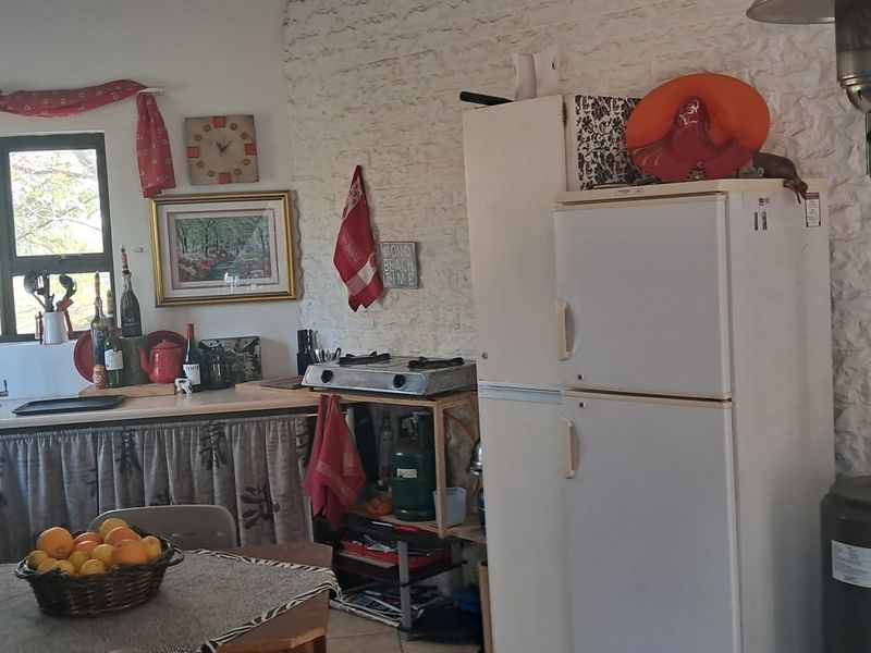 A rustic kitchen area featuring a textured brick wall, a functional sink, and basic counter space in a cottage-style setting.