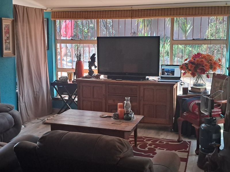 A cozy living room featuring large windows with security bars and laminate flooring, offering a comfortable and functional space.