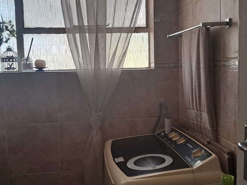 A functional laundry area featuring tiled walls, a basin, and a window, providing a practical space for household utility tasks.
