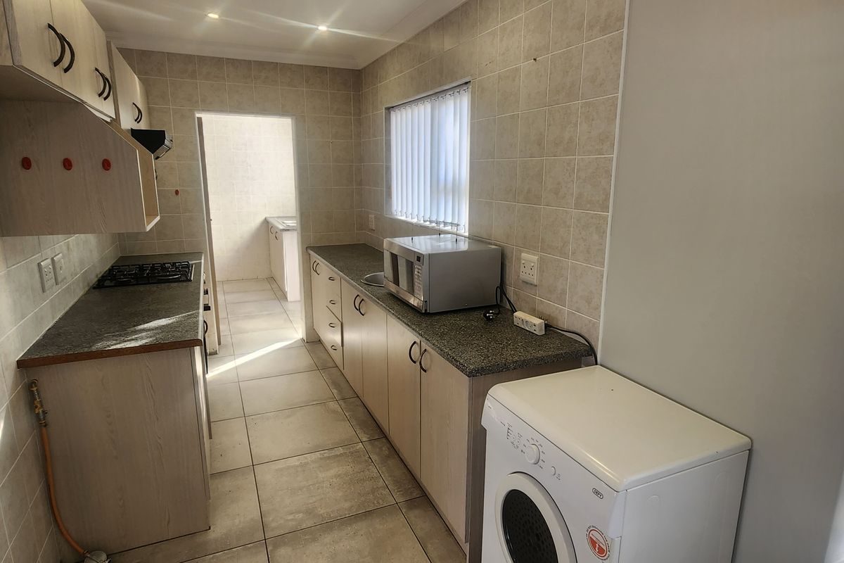 Functional kitchen featuring light wood-finish cabinetry, tiled backsplash, gas hob, and direct access to a scullery area.