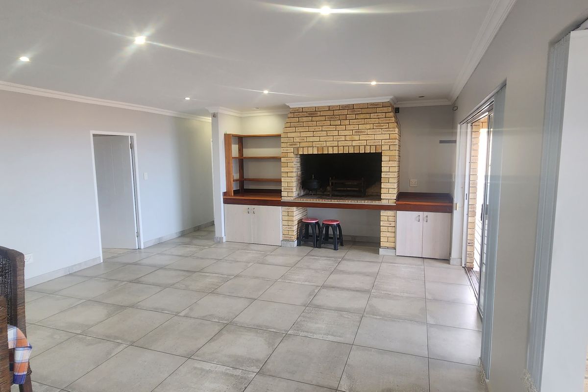 Spacious living area featuring large format floor tiles, recessed lighting, and a prominent built-in brick fireplace with integrated storage cabinetry.