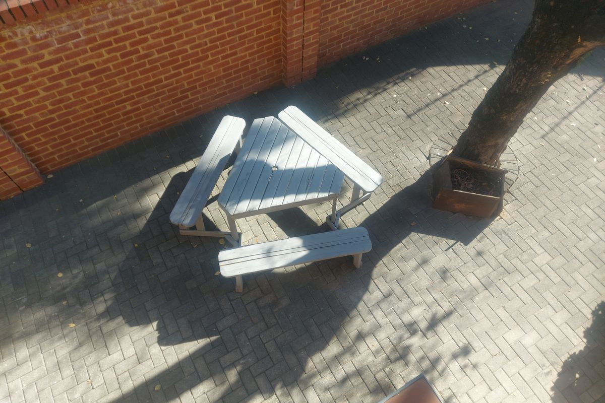 An elevated view of a paved rear courtyard area enclosed by a brick boundary wall.