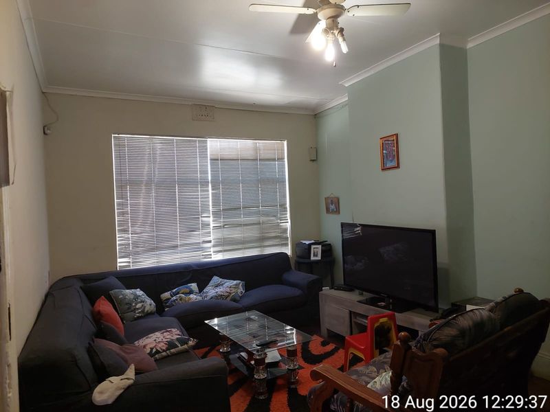 A living room featuring a ceiling fan, coving, and venetian blinds, providing a functional space for relaxation.