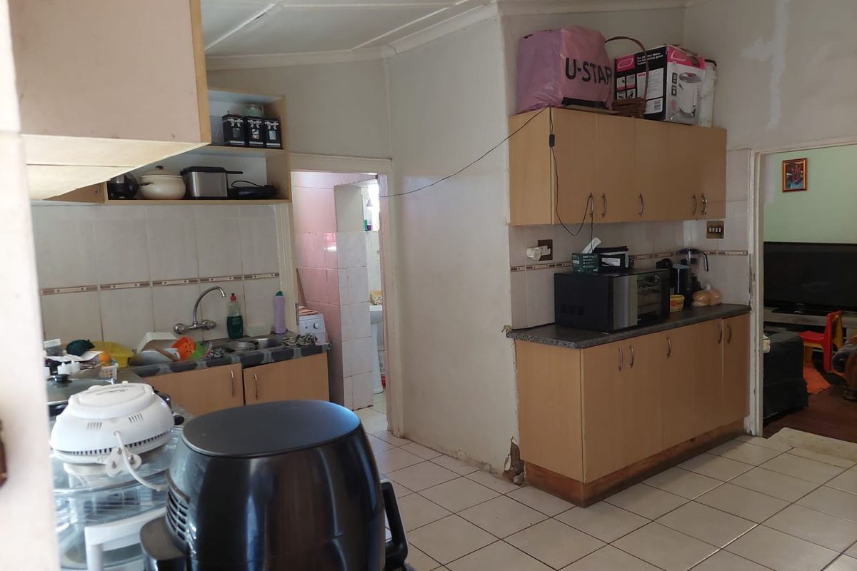 A functional kitchen featuring laminate cabinetry, tiled flooring, and a tiled backsplash, requiring cosmetic updates to improve its overall condition and aesthetic appeal.