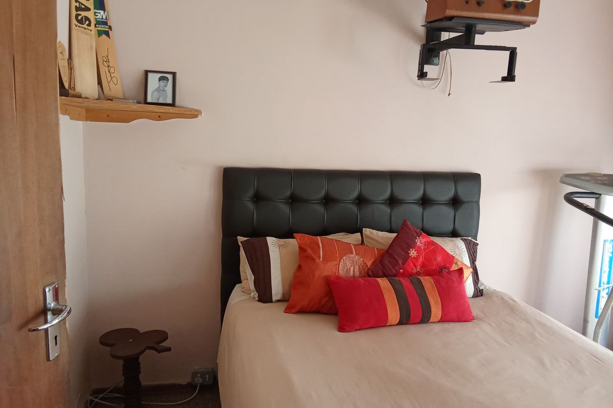 A standard bedroom featuring a wall-mounted shelf and neutral wall finishes, providing a functional space for rest.