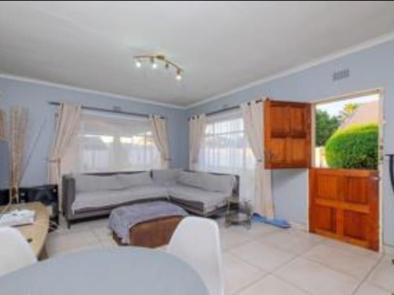A bright living room featuring tiled flooring and a traditional wooden stable door providing direct access to the garden.