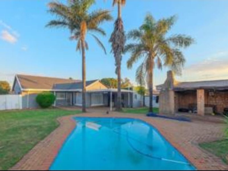 Rear garden featuring a swimming pool, brick-paved surround, and a covered outdoor entertainment area with a built-in braai.