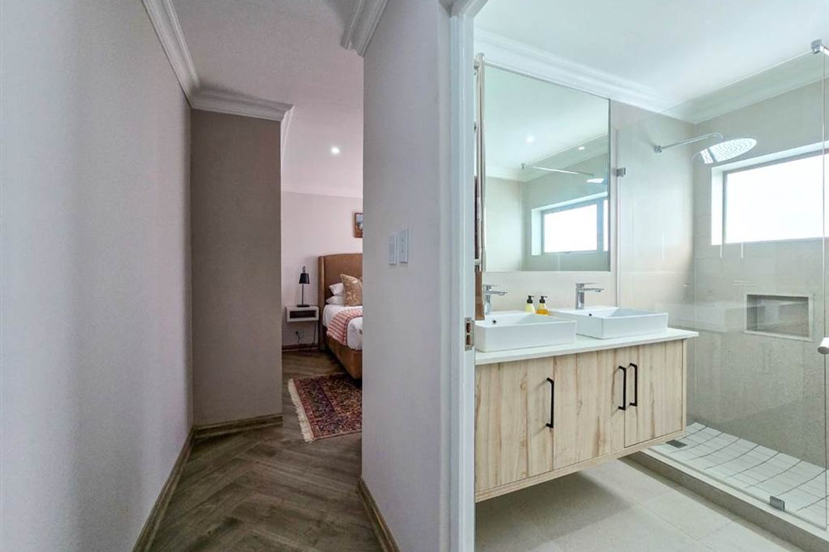Modern bathroom featuring a double vanity with vessel sinks, a spacious walk-in shower with glass screen, and elegant herringbone flooring.