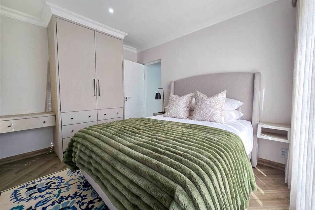 A well-maintained bedroom featuring built-in wardrobes, recessed downlighting, and modern laminate flooring, offering a clean and comfortable living space.