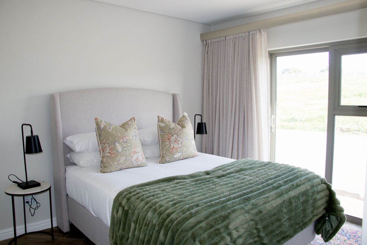 A well-maintained bedroom featuring neutral walls, modern flooring, and a sliding glass door providing natural light and outdoor access.