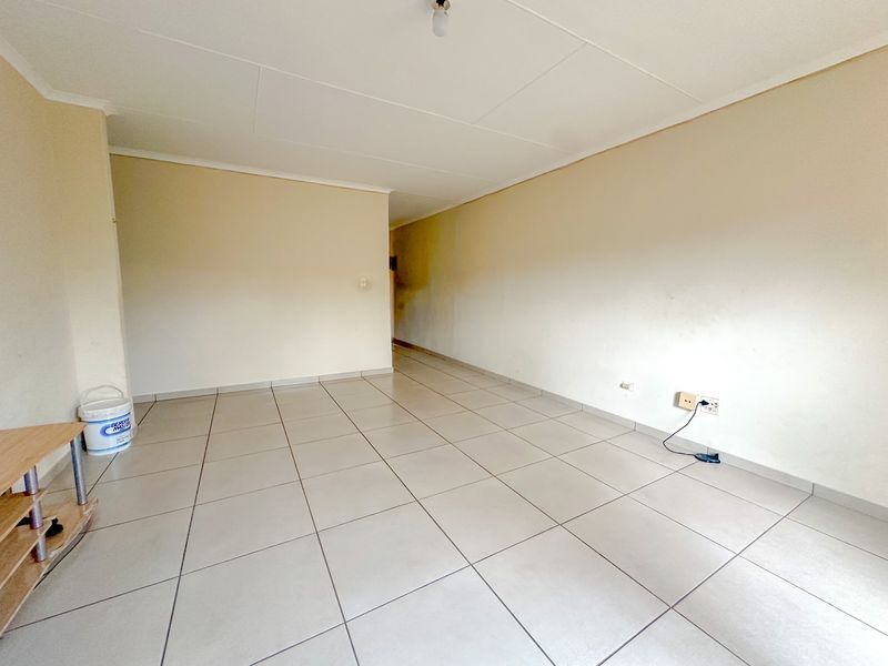 An empty living room featuring neutral tiled flooring and plain walls, offering a blank canvas for personalization and interior design updates.