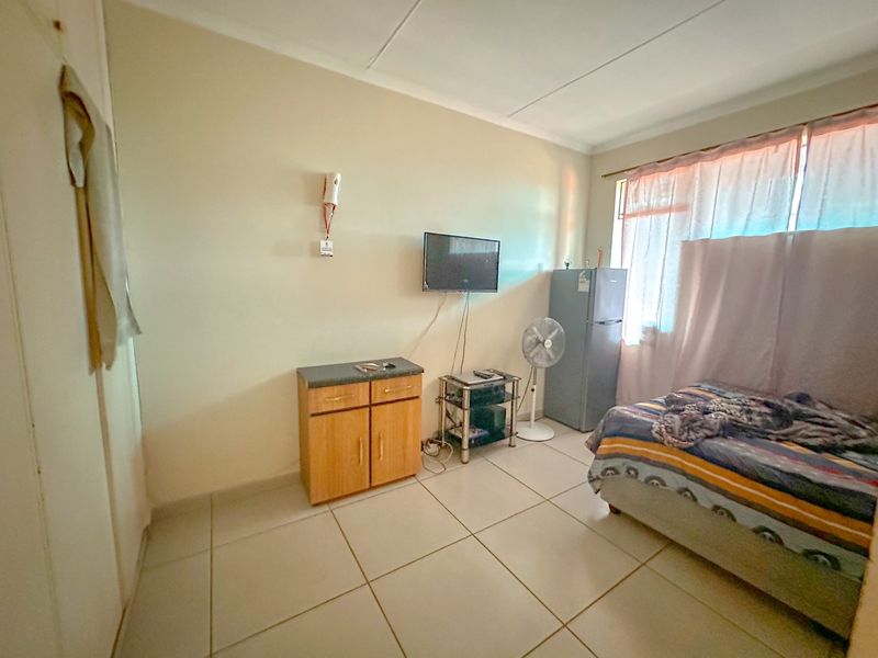 A functional bedroom featuring tiled flooring, a built-in cupboard, and an intercom system, offering a neutral space ready for personalization.