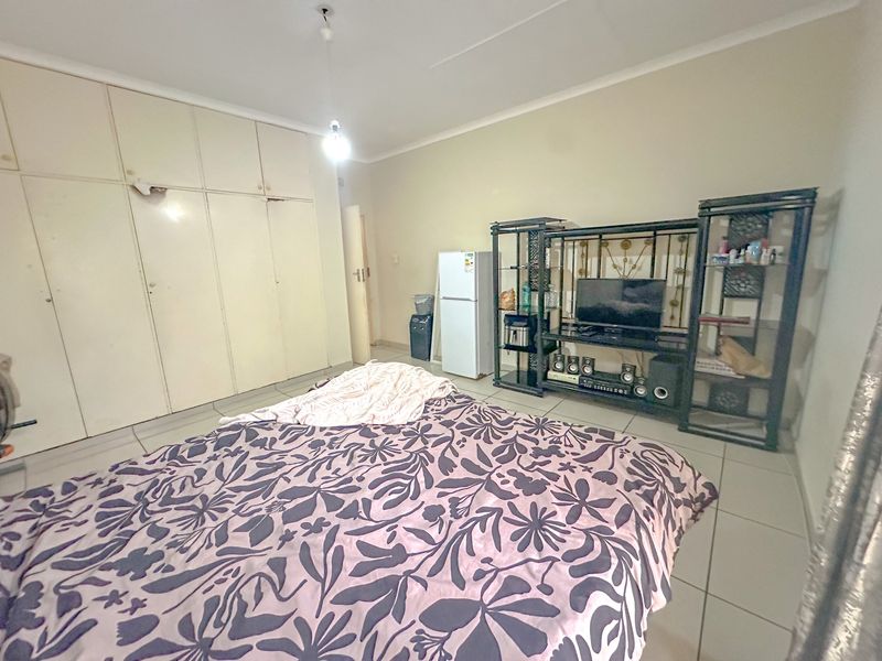 A bedroom featuring tiled flooring and extensive built-in cupboard storage, offering a functional space with potential for cosmetic updates.