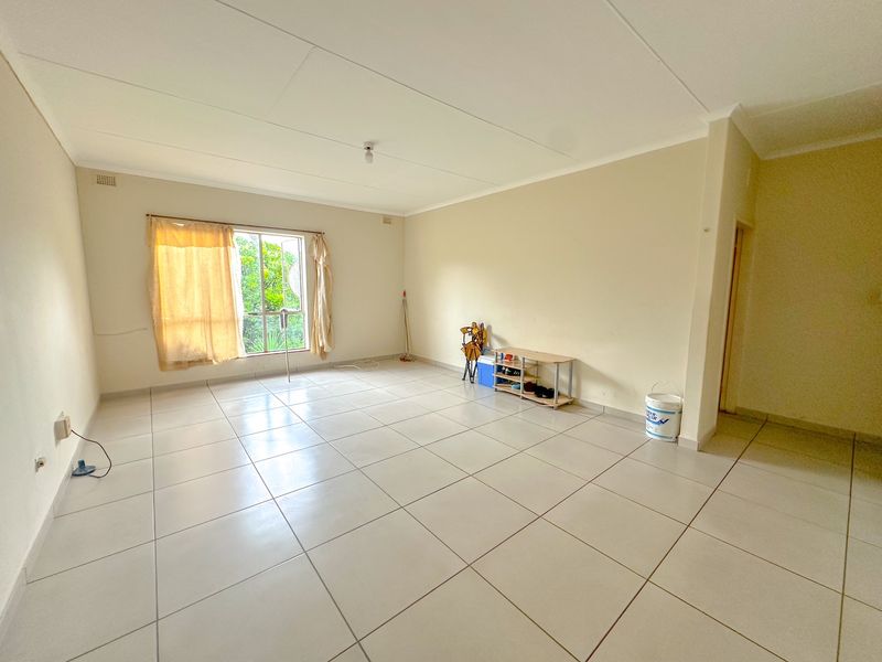 A spacious, empty living area featuring neutral tiled flooring and a coved ceiling, offering a blank canvas for interior design.