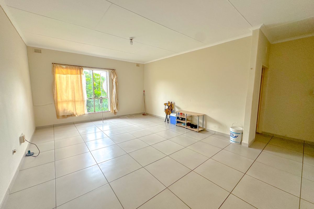 A spacious, empty living area featuring neutral tiled flooring and a coved ceiling, offering a blank canvas for interior design.