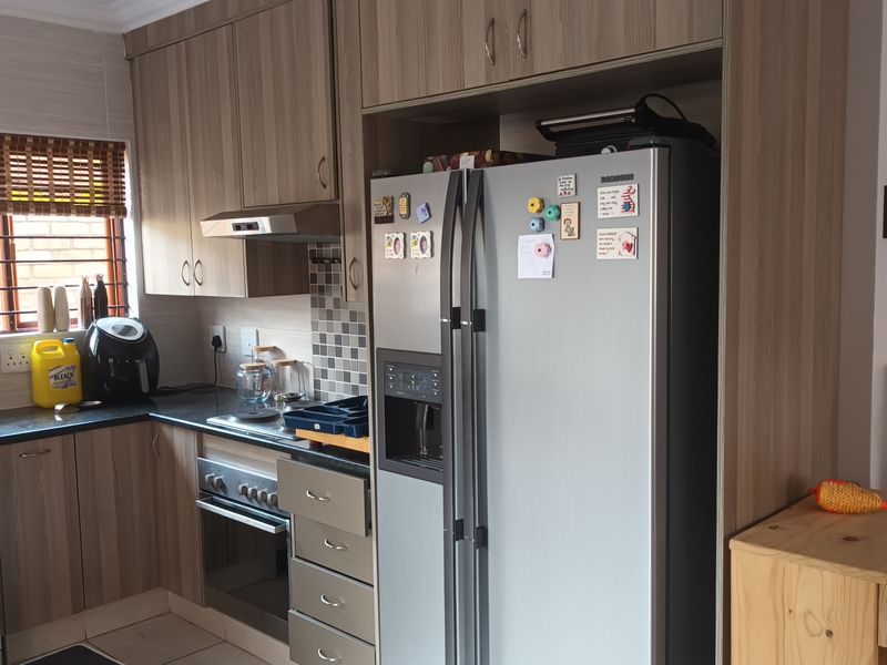 A functional kitchen featuring wood-look cabinetry, mosaic tile backsplash, built-in oven with extractor fan, and dedicated housing for a large double-door refrigerator.