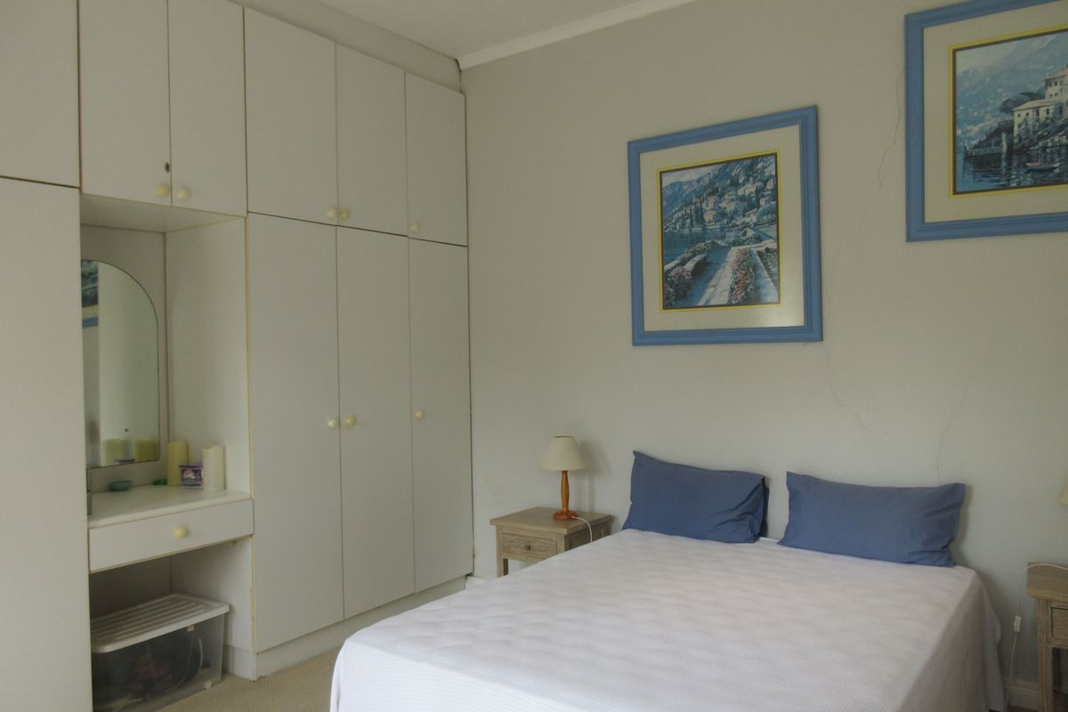 A bedroom featuring extensive built-in cupboards and a vanity unit, showing signs of wall cracking requiring maintenance.