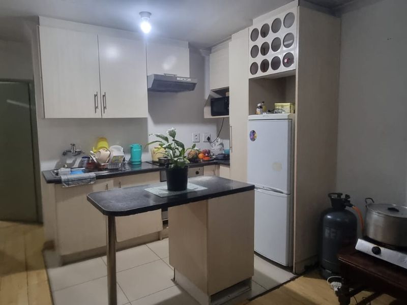 A functional kitchen featuring built-in cabinetry, a breakfast bar, and a combination of tiled and wooden flooring, offering a practical layout for daily use.