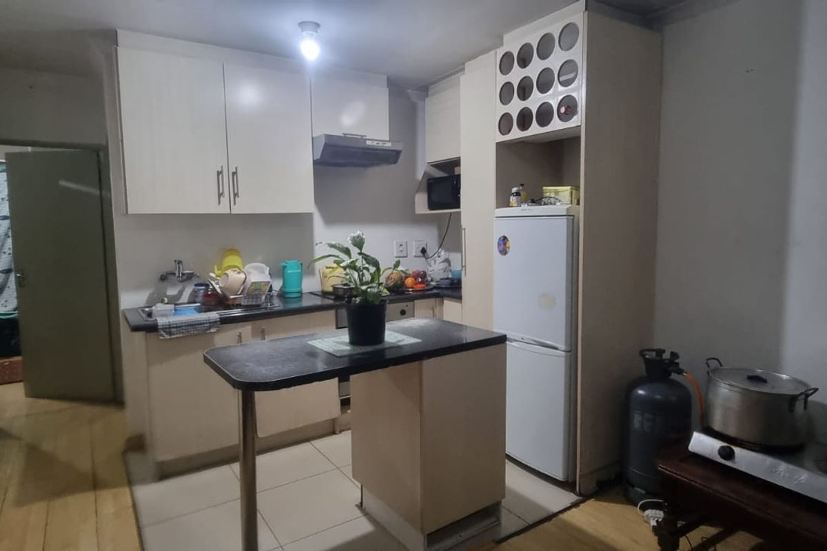 A functional kitchen featuring built-in cabinetry, a breakfast bar, and a combination of tiled and wooden flooring, offering a practical layout for daily use.