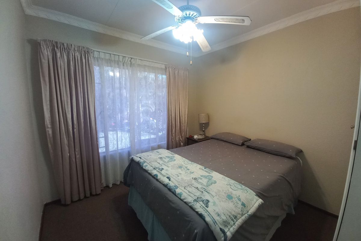 A bedroom featuring a ceiling fan, crown molding, and built-in wardrobe storage.