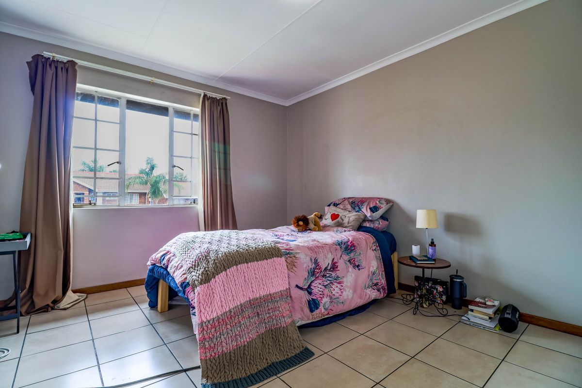 A functional bedroom featuring tiled flooring, coved ceilings, and a window with security bars, offering a neutral base for personalization.