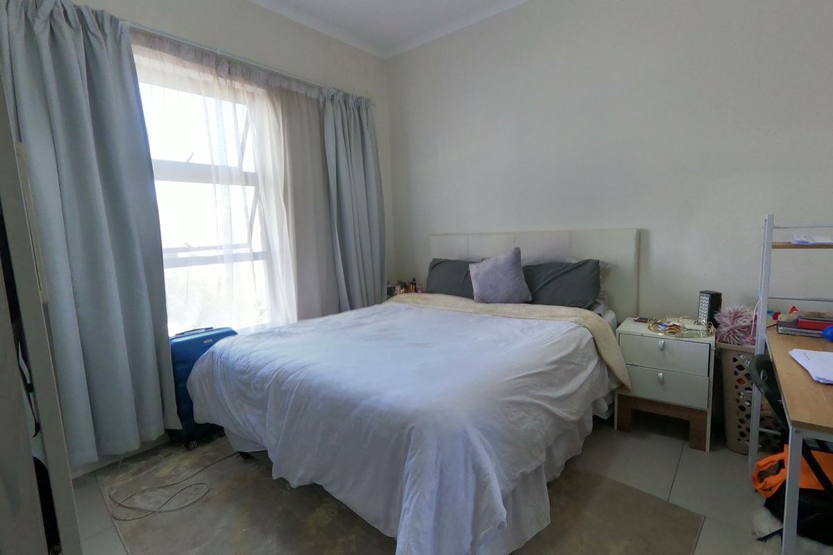 A functional bedroom featuring tiled flooring and a large window that allows for natural light.