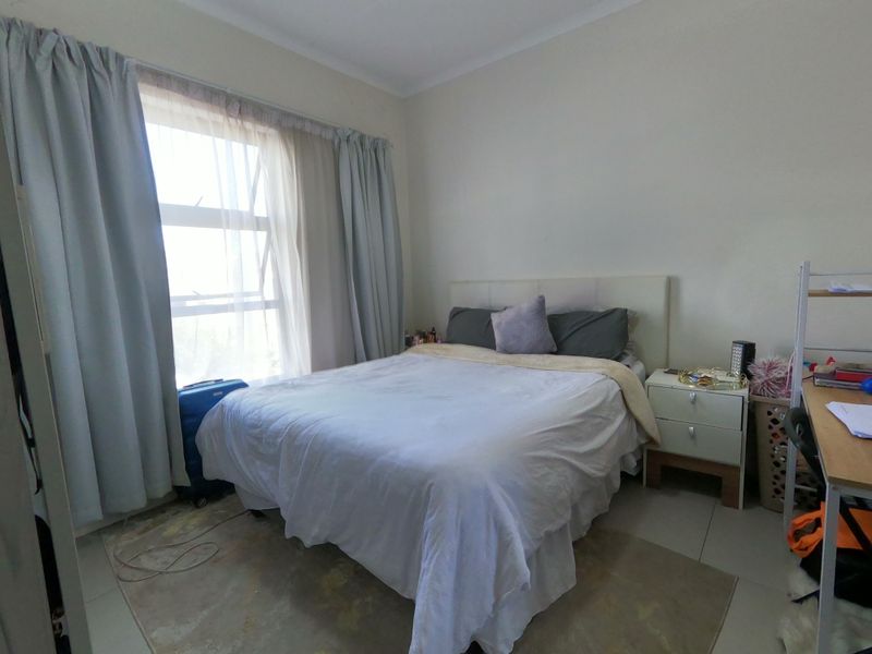 A functional bedroom featuring tiled flooring and a large window that allows for natural light.