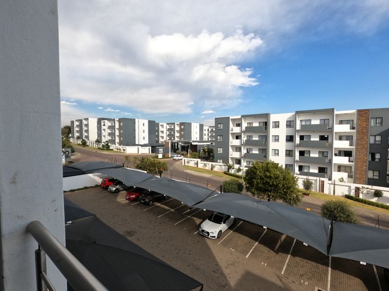 Elevated view overlooking a residential apartment complex with paved parking bays and shade cloth carports.