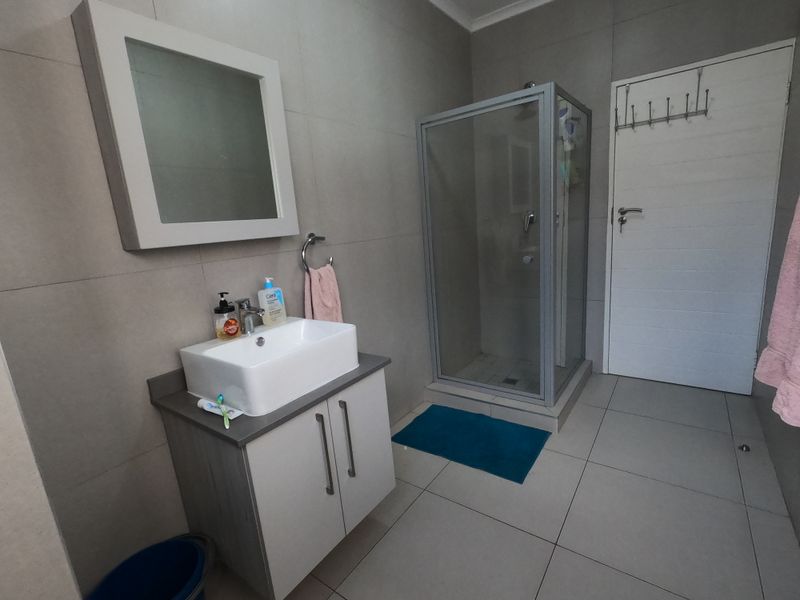 Modern bathroom featuring a vessel sink vanity, a glass-enclosed shower, and neutral floor-to-ceiling wall tiles.
