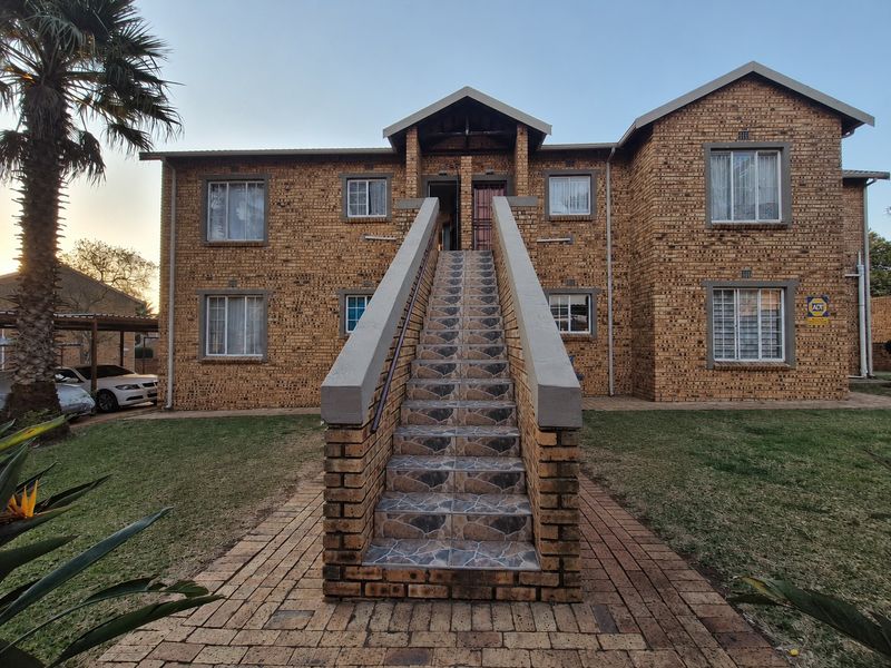Front elevation of a face brick apartment building featuring a central tiled staircase leading to the upper level entrance.