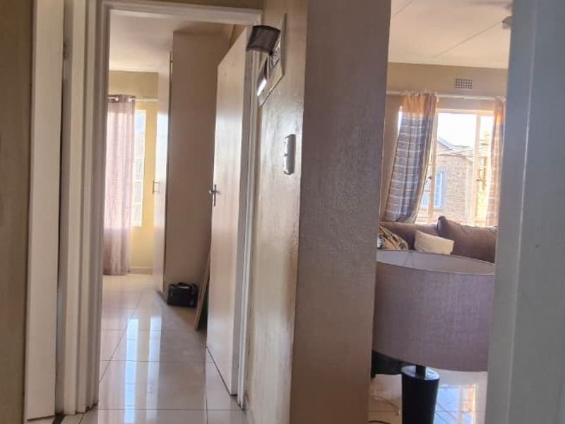 A functional hallway with tiled flooring connecting the living area to other rooms, featuring neutral wall finishes and standard internal door access.