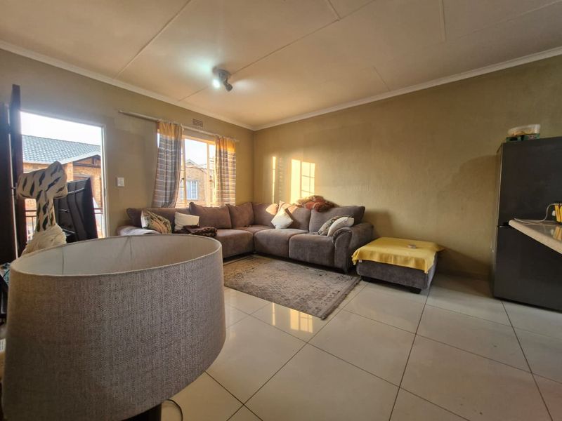 A living room featuring tiled flooring, neutral wall tones, and a sliding door providing access to the exterior.