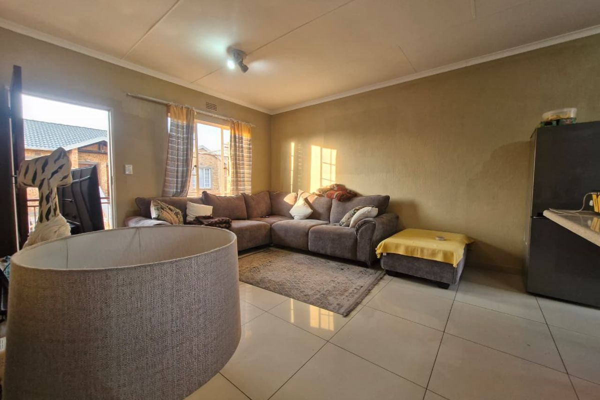 A living room featuring tiled flooring, neutral wall tones, and a sliding door providing access to the exterior.
