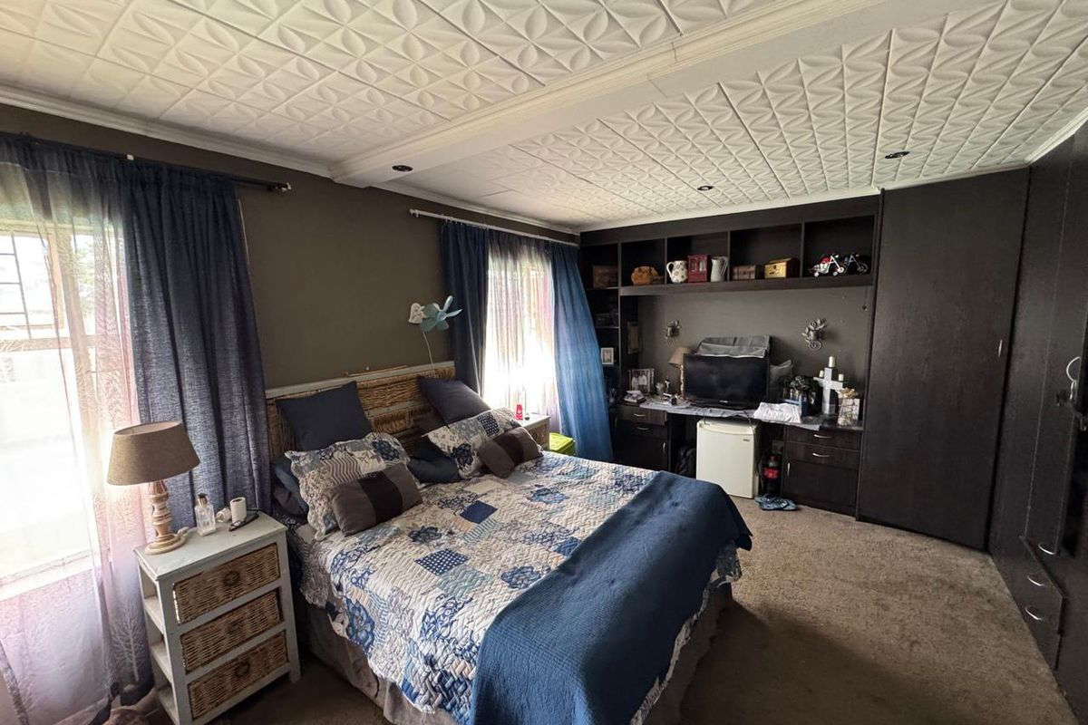 Spacious bedroom featuring built-in cabinetry, integrated shelving, and a unique textured ceiling finish, offering ample storage and a comfortable layout.