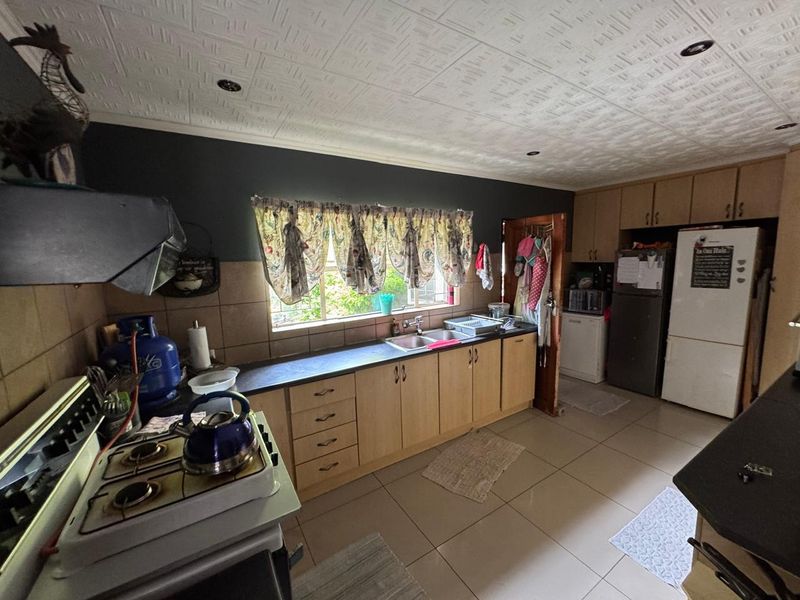 Functional kitchen featuring light wood cabinetry, tiled backsplash, integrated sink, and ample counter space with a gas stove setup.