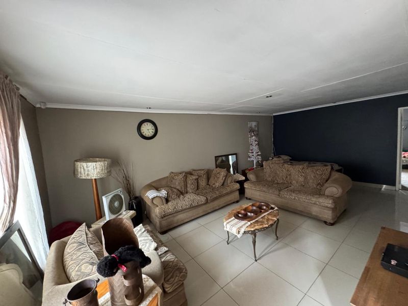 A spacious living room featuring large format floor tiles and a neutral color palette with a dark accent wall.